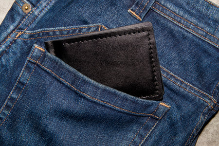 Black handmade leather wallet on blue jeans. Male background. View from above.の写真素材