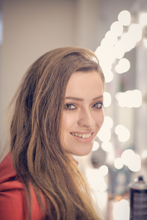 Beautiful young woman is smiling and posing on the camera in beauty salonの写真素材