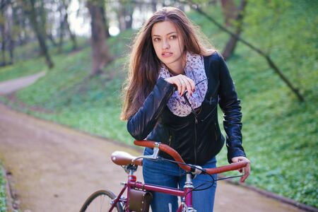 Beautiful young woman with vintage bicycle in a parkの写真素材