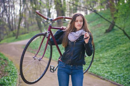 Beautiful young woman with vintage bicycle in a parkの写真素材