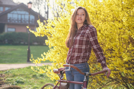 Beautiful young woman with vintage bicycle in a parkの写真素材