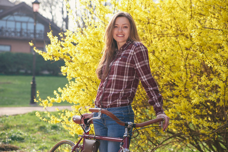 Beautiful young woman with vintage bicycle in a parkの写真素材