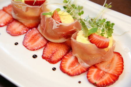 layered dessert with strawberries, biscuit cake and cream cheese on a dark wood backgroundの写真素材