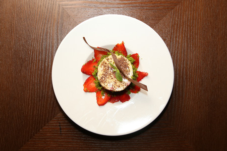 layered dessert with strawberries, biscuit cake and cream cheese on a dark wood backgroundの写真素材