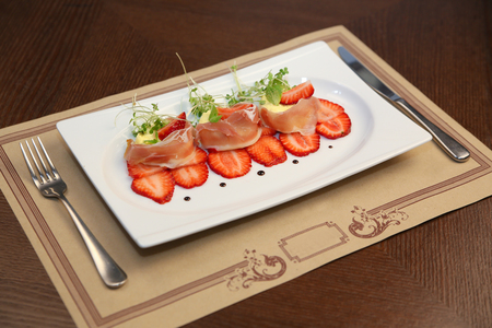 layered dessert with strawberries, biscuit cake and cream cheese on a dark wood backgroundの写真素材