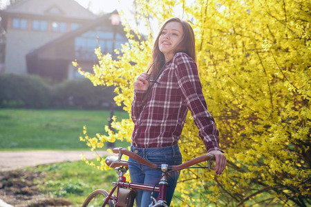 Beautiful young woman with vintage bicycle in a parkの写真素材