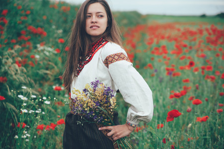 Beautiful girl in the poppy field. Ukrainian national clothesの写真素材
