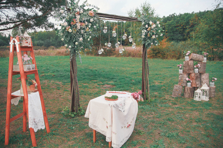 Rustic wedding photo zone. Hand made wedding decorations includes Photo Booth, wooden barrels and boxes, lanterns, suitcases and white flowersの写真素材