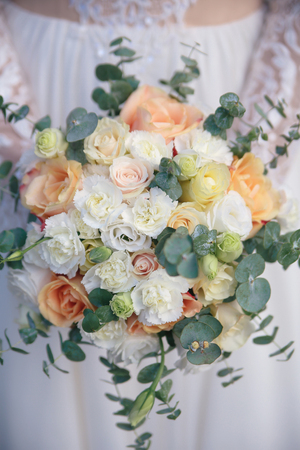 beautiful bouquet of different colors in the hands of the bride in a white dressの写真素材