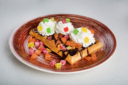 Plate of belgian waffles with cream, candied and chocolateの写真素材