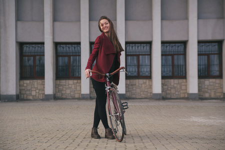 Sexy woman with vintage bike near modern concrete architecture skyscraperの写真素材