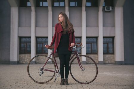 Sexy woman with vintage bike near modern concrete architecture skyscraperの写真素材