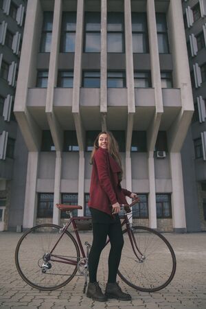 Sexy woman with vintage bike near modern concrete architecture skyscraperの写真素材
