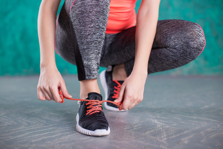 young woman runner tying shoelacesの写真素材