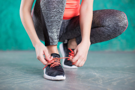 young woman runner tying shoelacesの写真素材