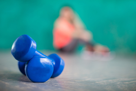 girls legs on sport shoes and dumbbells on a wooden backgroundの写真素材