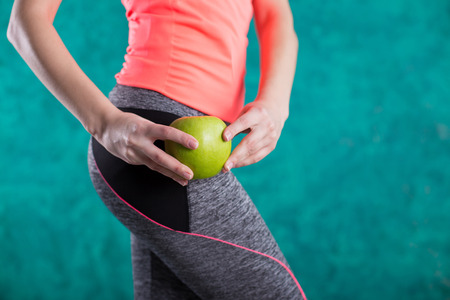 Diet. Healthy happy woman with apple and tape measure for diet and weight loss concept - isolated on the turquoise background. Sweets are unhealthy. Junk Food. Dieting, Healthy Eating.の写真素材