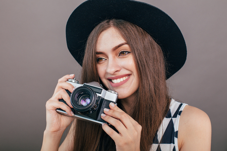 Stylish woman photographer with retro camera on the gray wall background. Image with copy spaceの写真素材