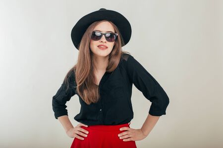 Young beautiful fashionable woman with trendy makeup in black hat and glasses on the gray background. Model looking at camera, wearing stylish eyeglasses. Female fashion, beauty concept.の写真素材