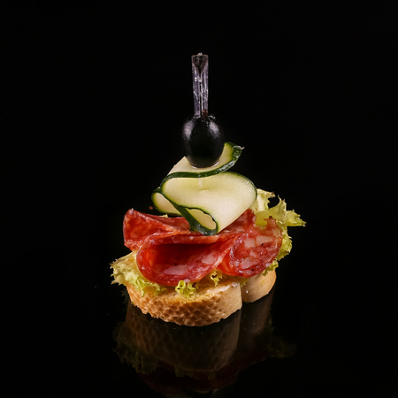 Delicious bruschetta with cured meat on black backgroundの写真素材