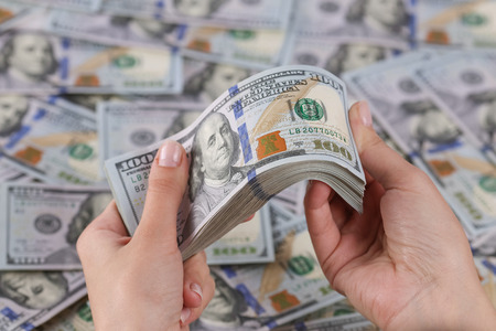 Man's hands holding 100 dollar bills.