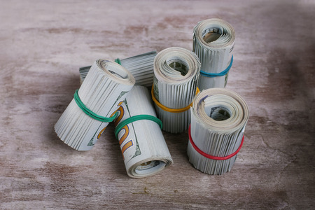 Rolled up American dollars on wooden backgroundの写真素材