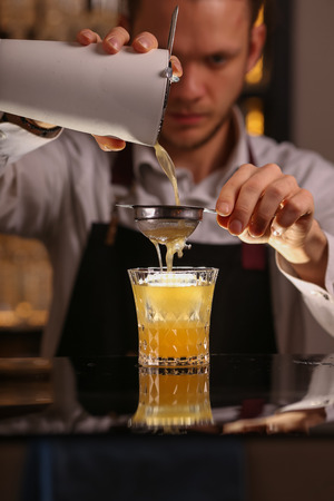 Fresh alcohol Penicillin cocktail with orange slice and ice cubes. Barmen is making Penicillin cocktailの写真素材