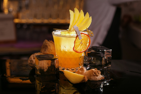 Fresh alcohol Penicillin cocktail with orange slice and ice cubes. Barmen is making Penicillin cocktailの写真素材