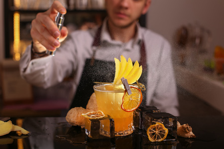 Fresh alcohol Penicillin cocktail with orange slice and ice cubes. Barmen is making Penicillin cocktailの写真素材