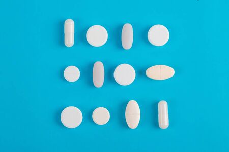 Assorted pharmaceutical medicine pills, tablets and capsules over blue backgroundの写真素材