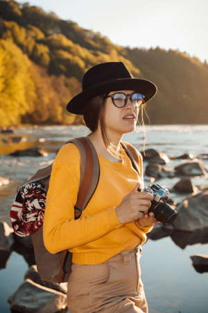 Young woman traveler is taking pictures of nature on a cameraの写真素材