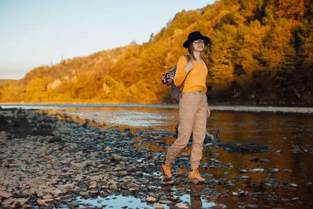 Young woman traveler stand with backpack on river nature backgroundの写真素材