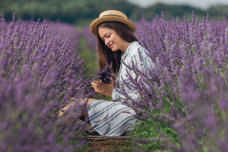 Young woman with lavender bouquet on violet flowers field backgroundの写真素材