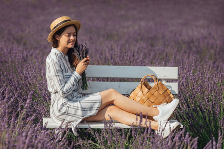 Young woman with lavender bouquet on violet flowers field backgroundの写真素材