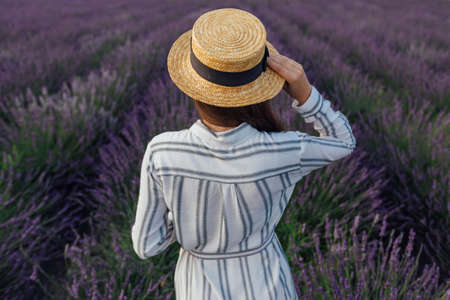 Young woman with lavender bouquet on violet flowers field background