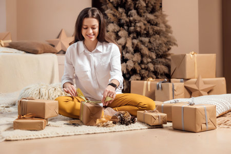 Young woman is wrapping christmas presents for holidays