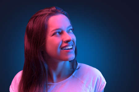 Neon close up portrait of young woman in white dress on dark blue backgroundの写真素材