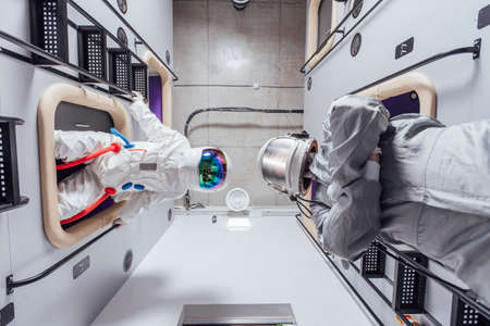 Portrait of astronauts in spacesuits in the sleeping module of the capsule hotel. View from belowの写真素材
