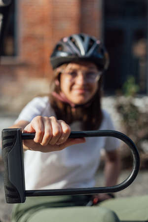 Young female in bicycle helmet hold bicycle U lockの写真素材