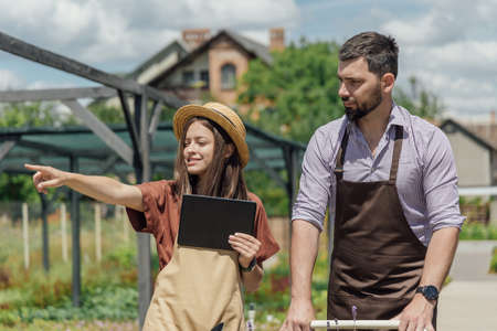 A couple of gardeners select plants for a customer at a garden centerの写真素材