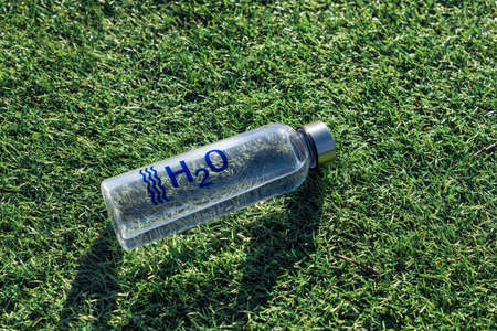 Water bottle on green grass with summer scene background