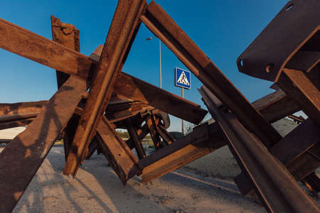 Rusty anti-tank hedgehogs on the wet grass on sunset background. War in Ukraineの写真素材