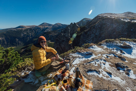 A woman enjoys a beautiful view of rocks and mountains while having a picnic with a tourist equipの写真素材