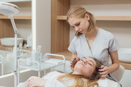 An expert cosmetologist performs an analysis of the patients facial skinの写真素材