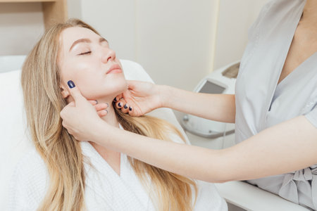 An expert cosmetologist performs an analysis of the patients facial skinの写真素材