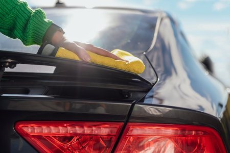 A young female cleaning and polishing her car with microfiber cloth. Concept of car taking care