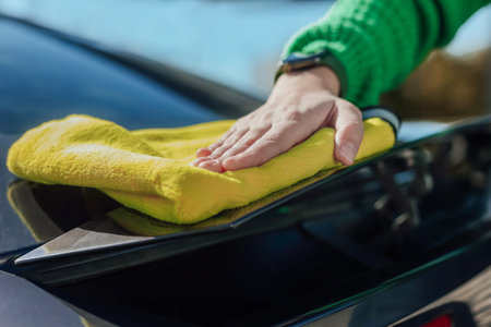 A young female cleaning and polishing her car with yellow microfiber cloth. Concept of car taking...