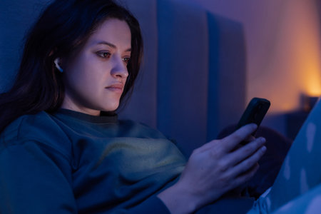 Woman surfing on internet with smartphone late at night, because of blackout