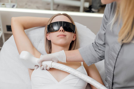 Beautician removes hair on beautiful females armpit using a laser hair removal in Beauty clinicの写真素材