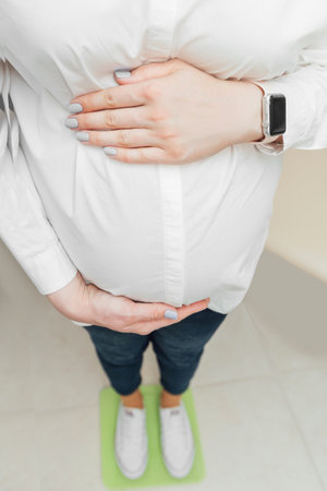 Young pregnant woman touching her belly and caring about her healthの写真素材